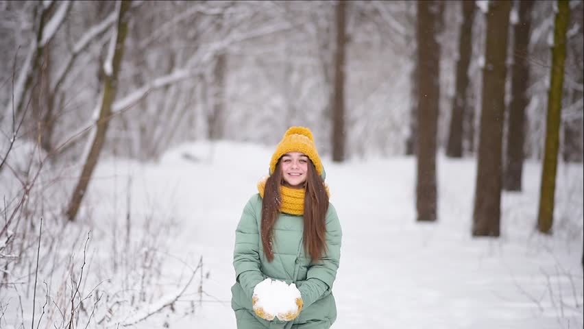 Ein Mädchen mit einem gelben Hut mitten im Schnee.