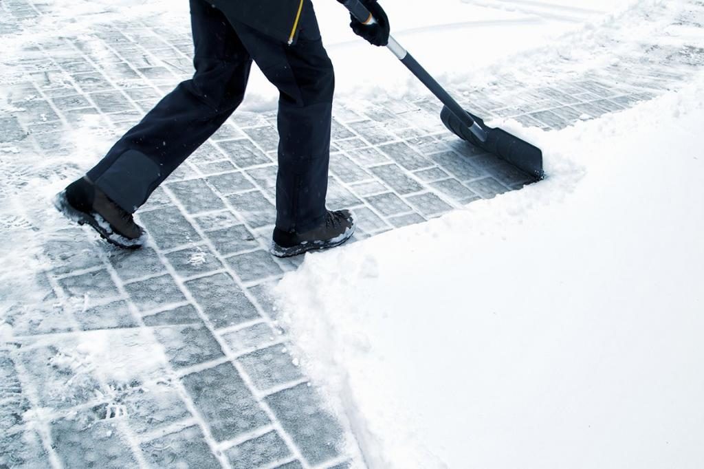 Mann räumt den Schnee mit einer Schaufel weg