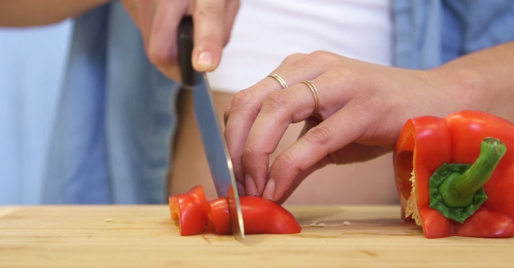 Ein Mann schneidet eine rote Paprika.