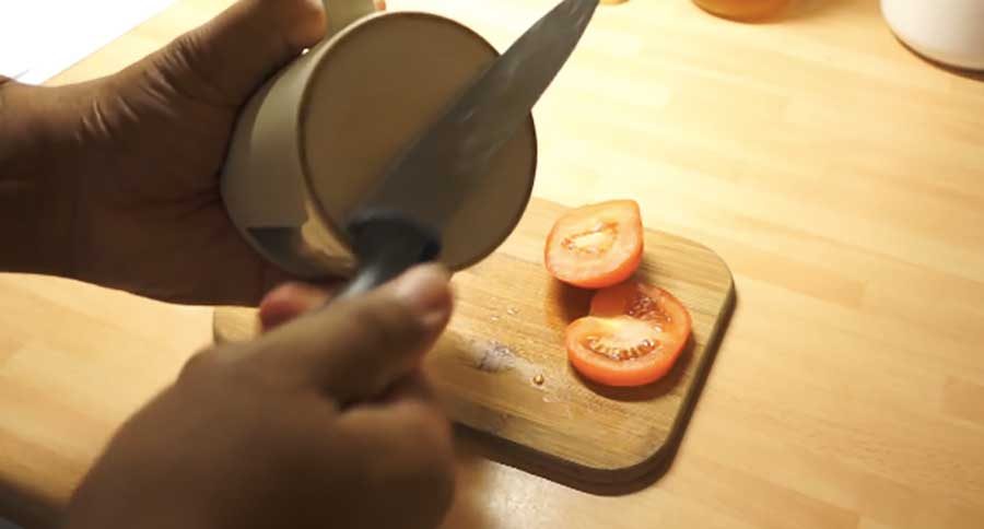 Ein Mann schneidet Tomaten mit einem Küchenmesser.