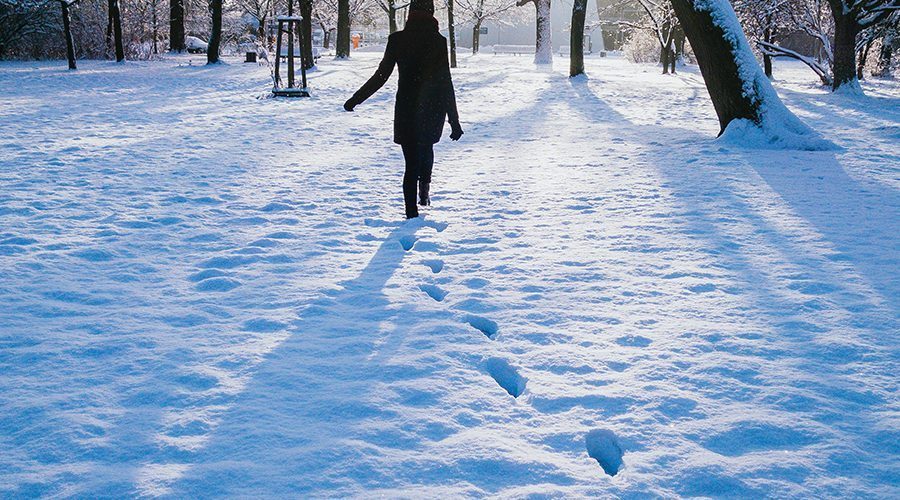 Ein Mädchen, das im Schnee spazieren geht