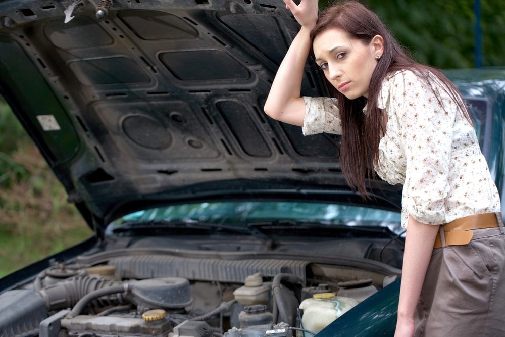 Mädchen steht neben einem kaputten Auto